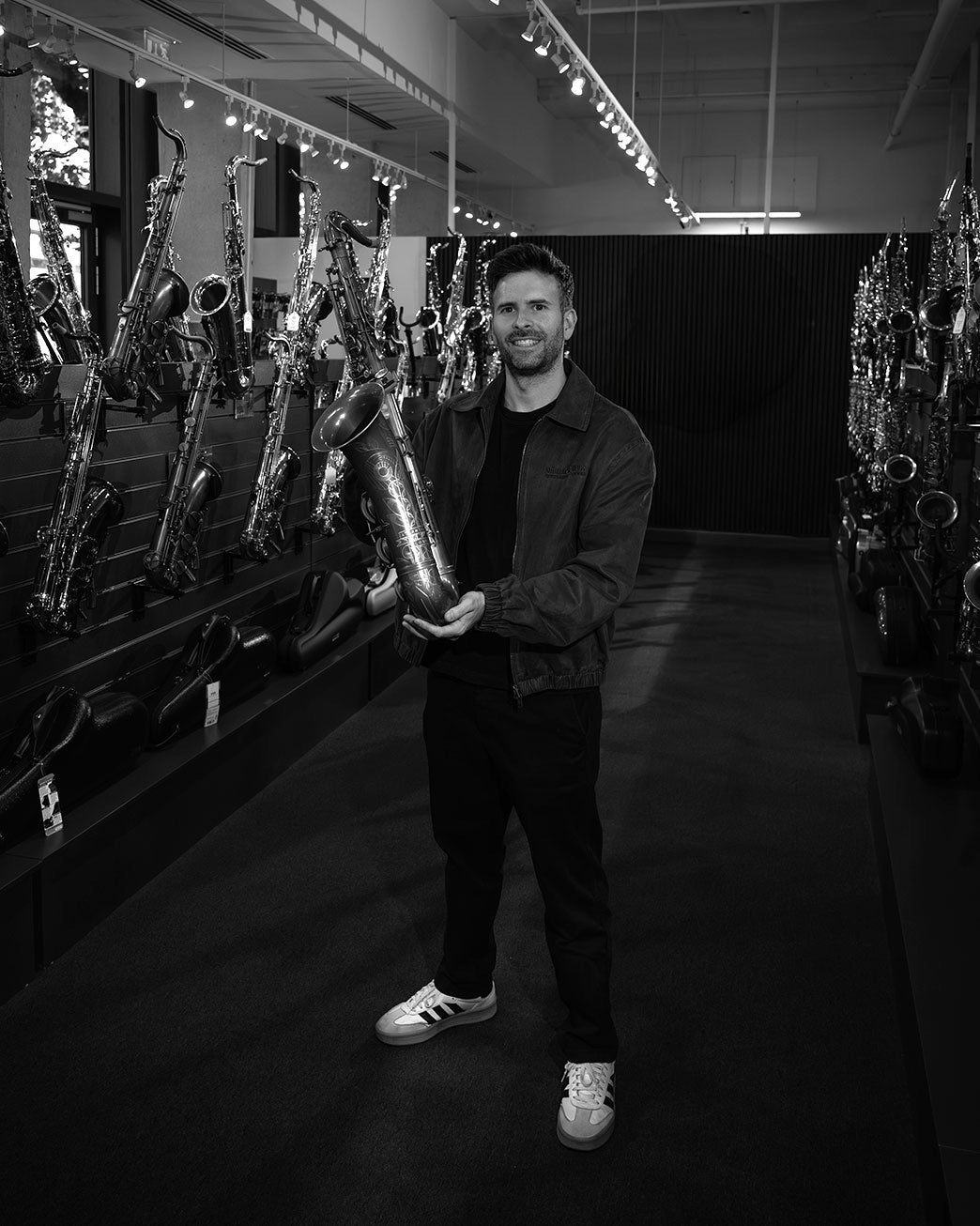 Jamie Straker holding an Atlantic London saxophone in a saxophone showroom
